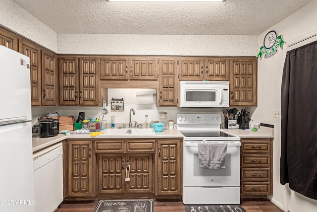 kitchen featuring dark wood-style flooring, light countertops, a sink, a textured ceiling, and white appliances