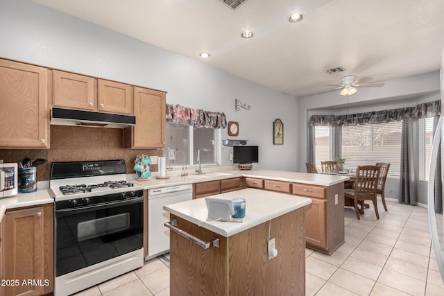 kitchen with white dishwasher, light tile patterned flooring, under cabinet range hood, a sink, and range with gas cooktop