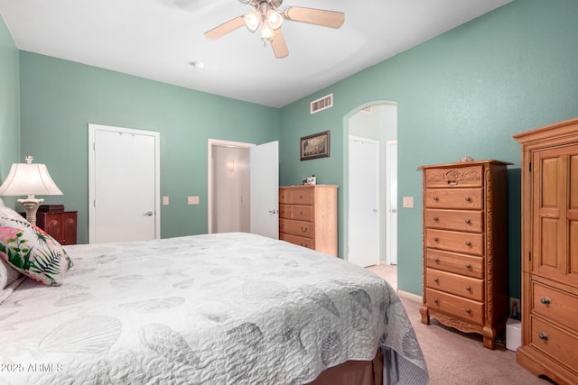 bedroom with arched walkways, light carpet, visible vents, and a ceiling fan