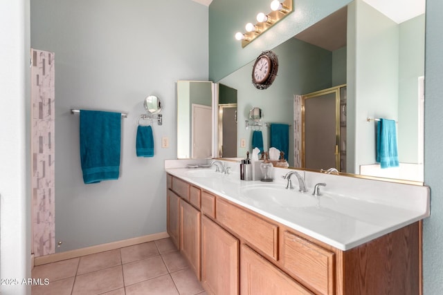 bathroom with a stall shower, double vanity, a sink, and tile patterned floors