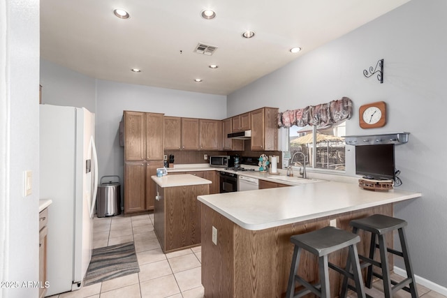 kitchen with white refrigerator with ice dispenser, visible vents, stainless steel microwave, gas range oven, and a sink