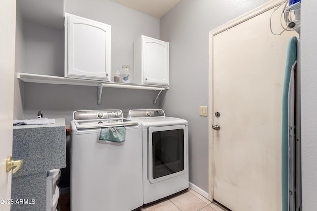 laundry area featuring cabinet space, light tile patterned floors, baseboards, and washing machine and clothes dryer