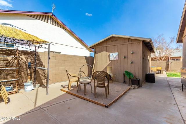 view of patio featuring a fenced backyard, a shed, and an outbuilding