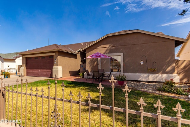 view of front facade with a garage, a front yard, fence, and stucco siding