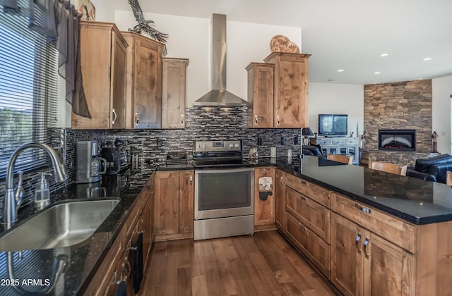 kitchen featuring dark stone counters, sink, stainless steel electric range, and wall chimney range hood