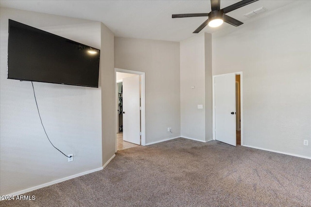 carpeted spare room featuring ceiling fan and a high ceiling