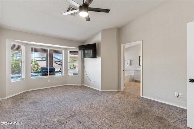 unfurnished bedroom with ensuite bathroom, vaulted ceiling, light colored carpet, and ceiling fan