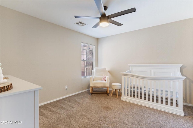 carpeted bedroom featuring a crib and ceiling fan