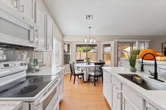 kitchen with white cabinets, sink, a wealth of natural light, and white appliances