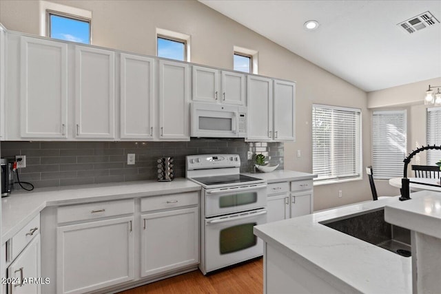 kitchen with lofted ceiling, backsplash, light wood-type flooring, white cabinets, and white appliances