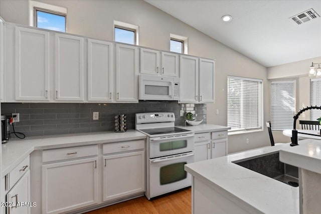 kitchen featuring white appliances, white cabinetry, and plenty of natural light