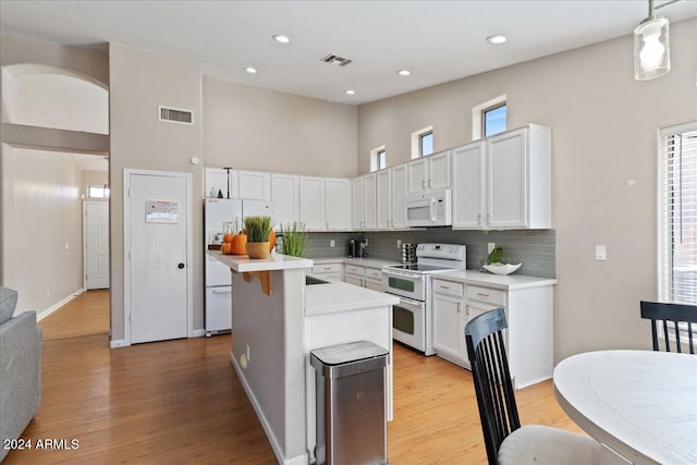 kitchen with white appliances, light hardwood / wood-style floors, a wealth of natural light, and hanging light fixtures