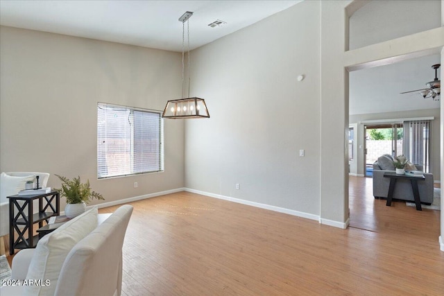 sitting room with a high ceiling, light wood-type flooring, and ceiling fan