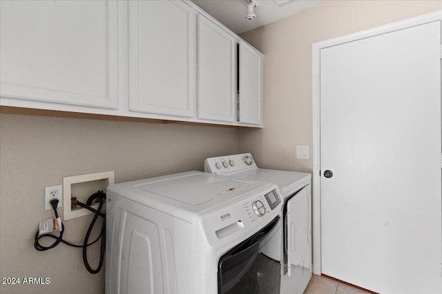 washroom featuring light tile patterned floors, cabinets, and washer and clothes dryer