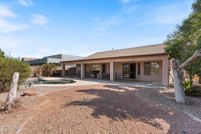 back of property featuring a patio area and a fenced in pool