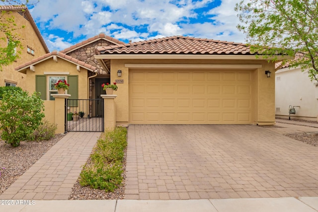 view of front facade featuring stucco siding, a gate, a tile roof, decorative driveway, and an attached garage