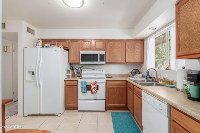 kitchen featuring light tile patterned flooring, white appliances, and sink