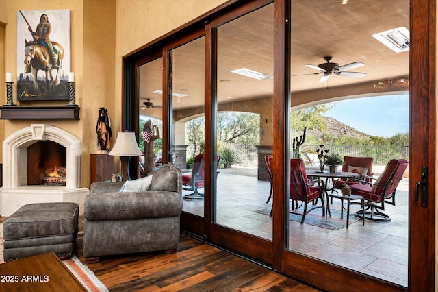 doorway to outside featuring ceiling fan and a warm lit fireplace