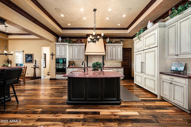 kitchen featuring a raised ceiling, a chandelier, oven, dark wood-style flooring, and ornamental molding