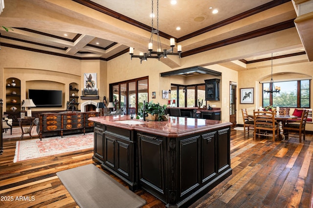 kitchen with a chandelier, dark cabinetry, crown molding, a sink, and dark wood-type flooring