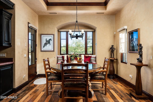 dining area featuring dark wood-type flooring, a chandelier, baseboards, ornamental molding, and a tray ceiling