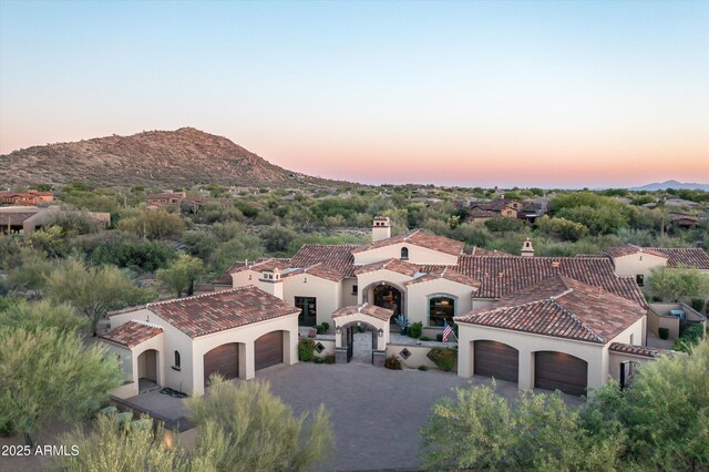 view of front of house with an attached garage, stucco siding, driveway, a tile roof, and a mountain view