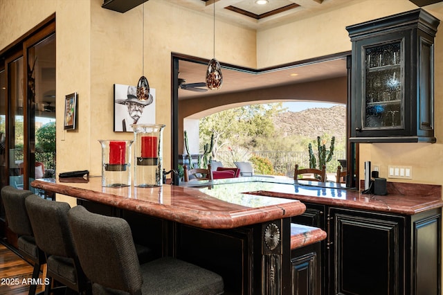 indoor wet bar with a towering ceiling, healthy amount of natural light, beam ceiling, coffered ceiling, and ceiling fan
