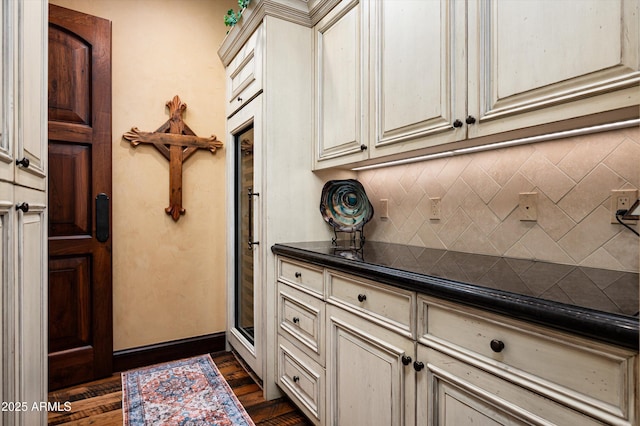 kitchen featuring cream cabinetry, dark countertops, tasteful backsplash, and dark wood finished floors
