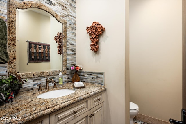 half bath featuring tasteful backsplash, toilet, vanity, and baseboards