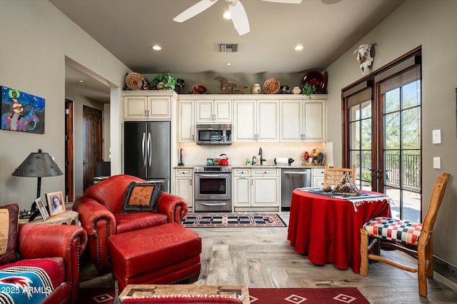 kitchen featuring stainless steel appliances, backsplash, a sink, light countertops, and a ceiling fan