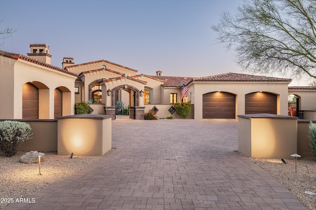 mediterranean / spanish house featuring stucco siding, a garage, decorative driveway, and a tile roof