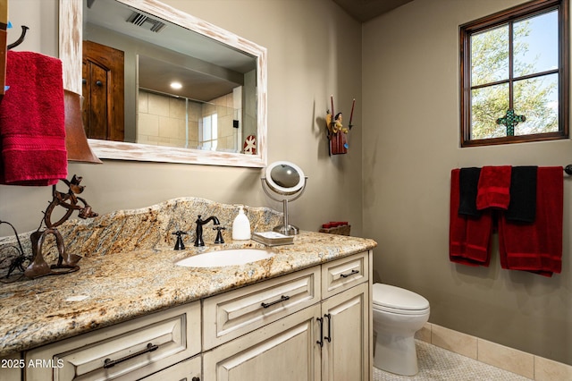 bathroom featuring tile patterned flooring, toilet, vanity, and tiled shower