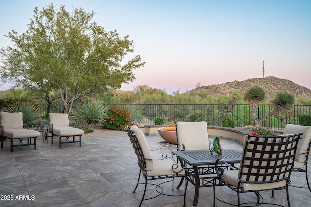 view of patio featuring fence, a mountain view, and outdoor dining space