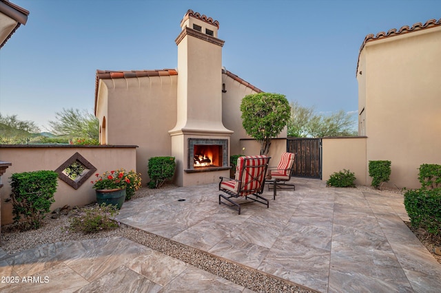 view of patio / terrace with a warm lit fireplace and fence