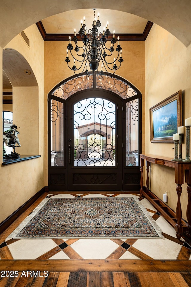 entrance foyer featuring a chandelier, crown molding, baseboards, plenty of natural light, and arched walkways