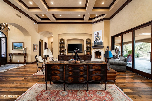 living room with a towering ceiling, wood-type flooring, ornamental molding, beam ceiling, and coffered ceiling