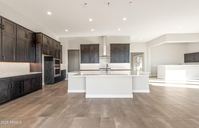 kitchen featuring dark brown cabinetry, an island with sink, appliances with stainless steel finishes, light countertops, and recessed lighting