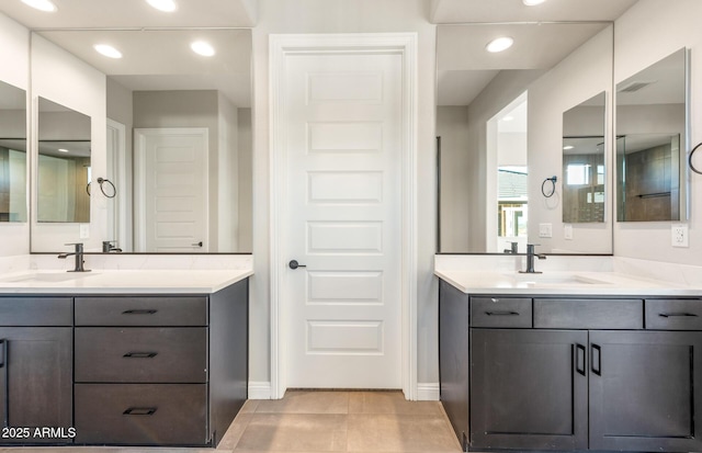 full bath featuring recessed lighting, two vanities, and a sink