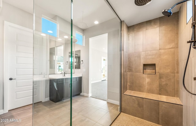 full bathroom featuring tile patterned floors, walk in shower, vanity, and baseboards