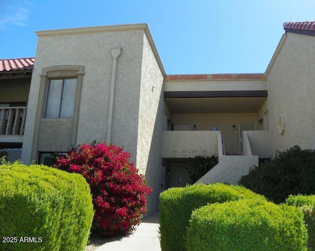 exterior space with a tile roof and stucco siding