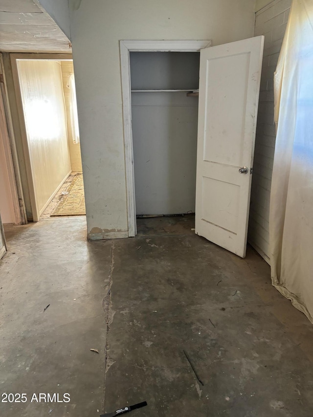 unfurnished bedroom with concrete flooring and a closet