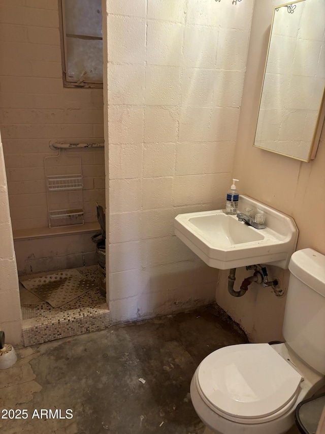 bathroom with toilet, sink, and concrete floors