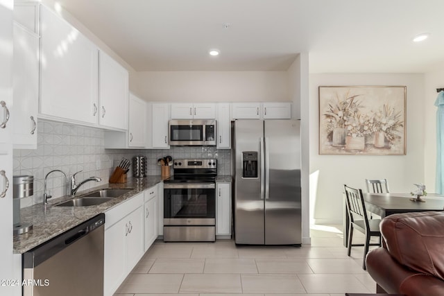 kitchen with dark stone counters, white cabinetry, sink, and stainless steel appliances