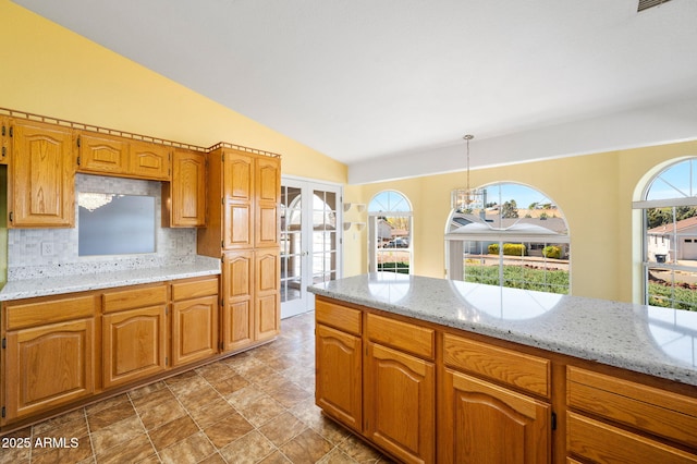 4701 N Sheridan Ln, Prescott Valley, AZ 86314 - kitchen with french doors, decorative backsplash, lofted ceiling, light stone counters, and a chandelier