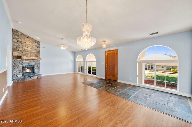 4701 N Sheridan Ln, Prescott Valley, AZ 86314 - unfurnished living room featuring a chandelier, ceiling fan, wood finished floors, a stone fireplace, and vaulted ceiling