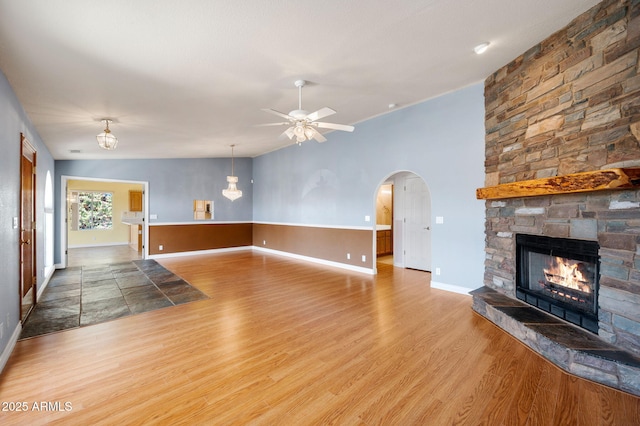 4701 N Sheridan Ln, Prescott Valley, AZ 86314 - unfurnished living room featuring a stone fireplace, baseboards, a ceiling fan, and light wood-style flooring