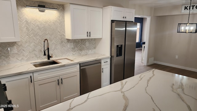 kitchen featuring stainless steel appliances, decorative light fixtures, light stone countertops, and sink