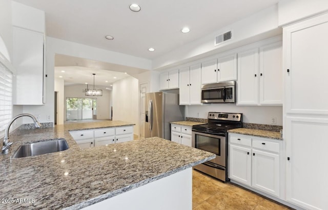 kitchen with pendant lighting, kitchen peninsula, sink, white cabinetry, and stainless steel appliances