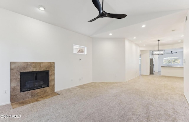 unfurnished living room featuring vaulted ceiling, ceiling fan, a fireplace, and light colored carpet