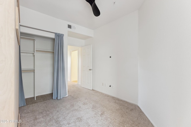 unfurnished bedroom featuring ceiling fan, light colored carpet, and a closet